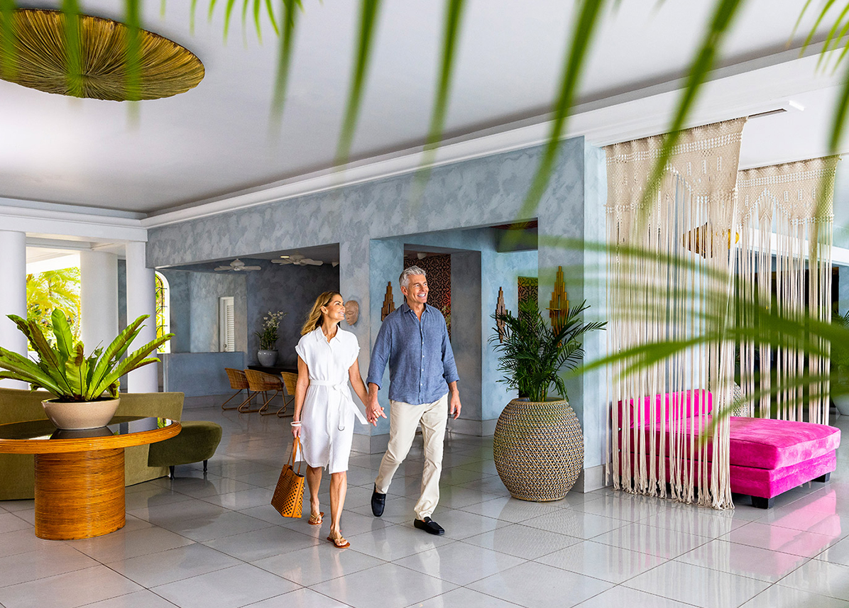 a man and woman holding hands and walking in a hotel lobby