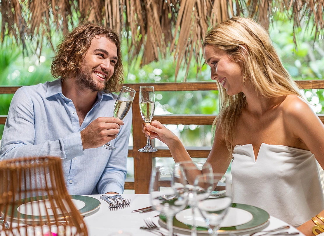 a man and woman sitting at a table with glasses of champagne