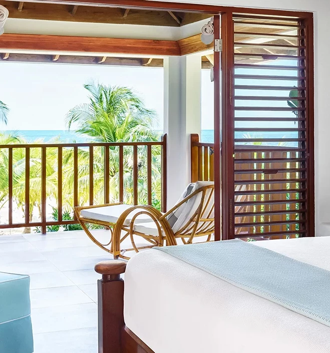 a room with a bed and a chair and a deck with a view of the ocean