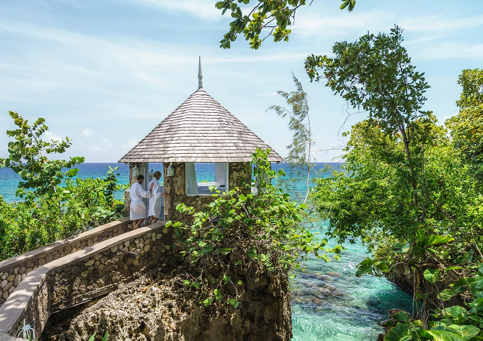 a couple of people standing on a stone structure by a body of water