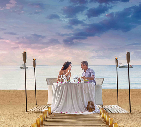 a man and woman sitting at a table on a beach