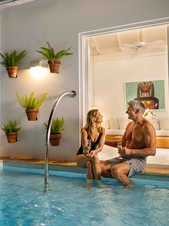 a man and woman sitting on a pool edge