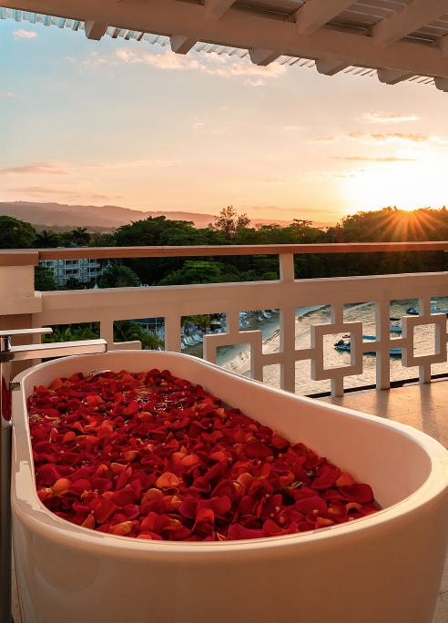 a bathtub full of rose petals on a balcony with a sunset