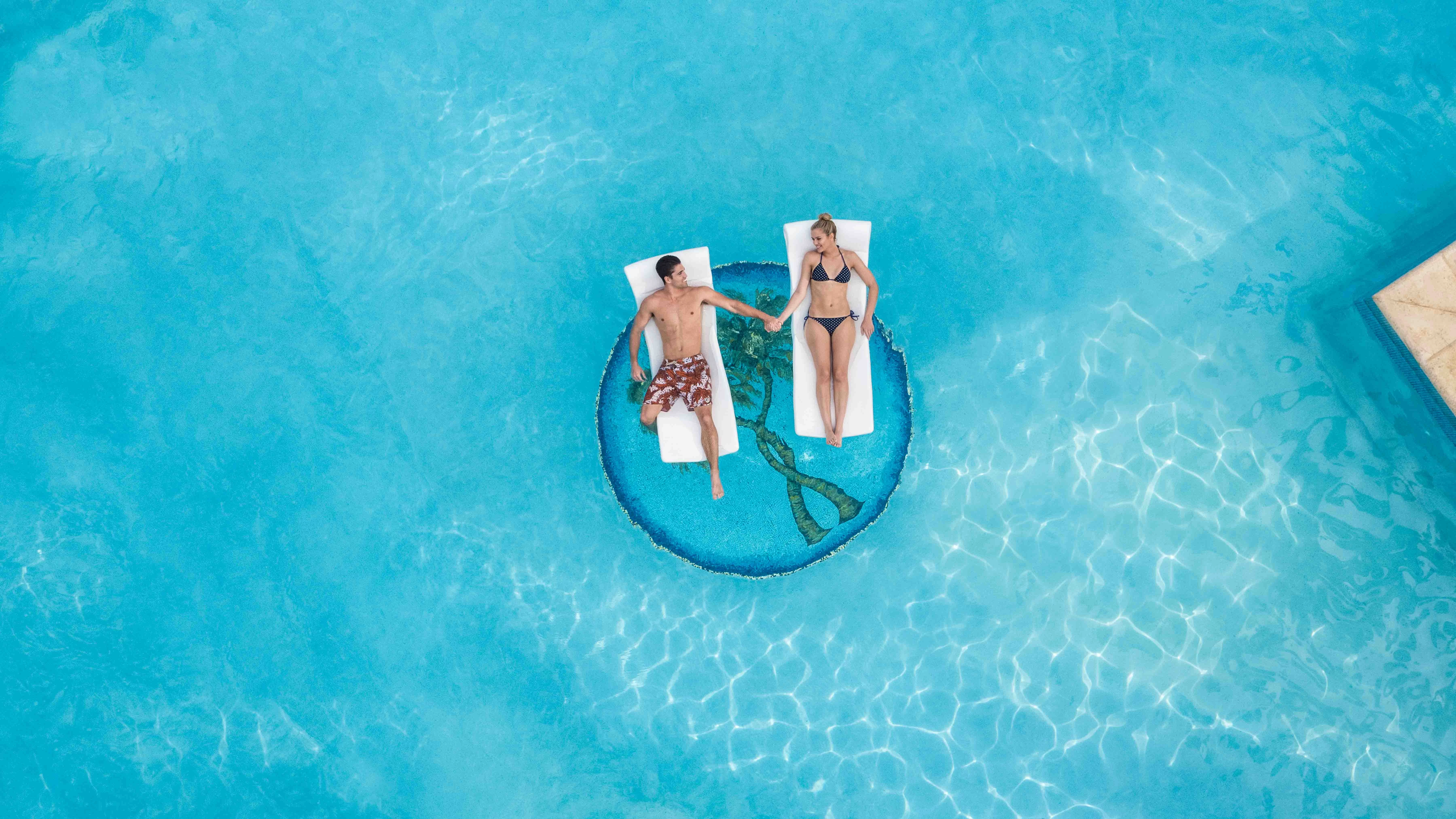a man and woman on a floating raft in a pool