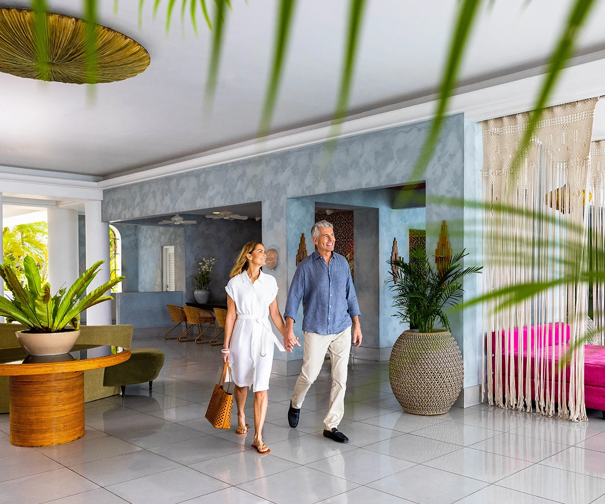 a man and woman holding hands walking in a hotel lobby