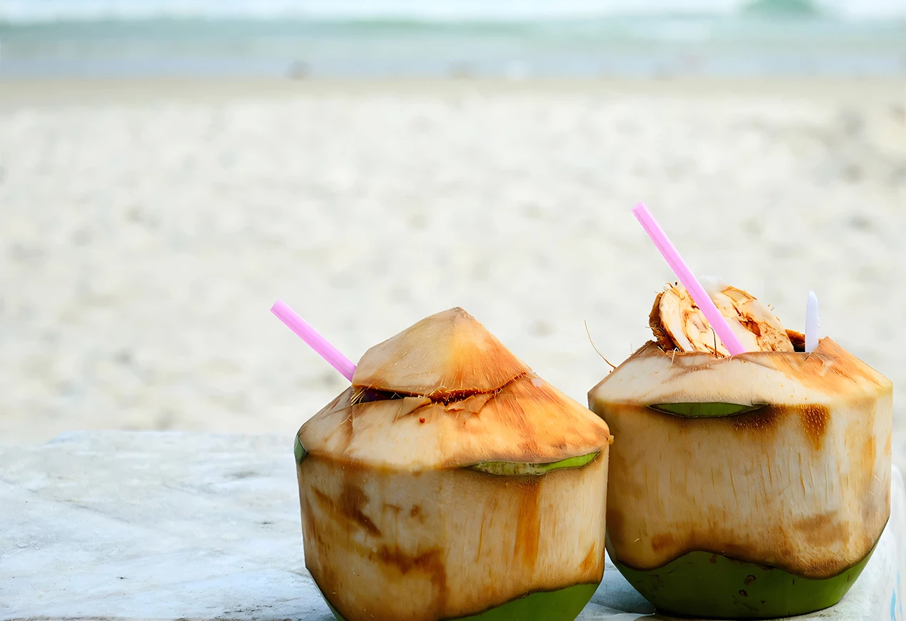 two coconuts with straws on a beach