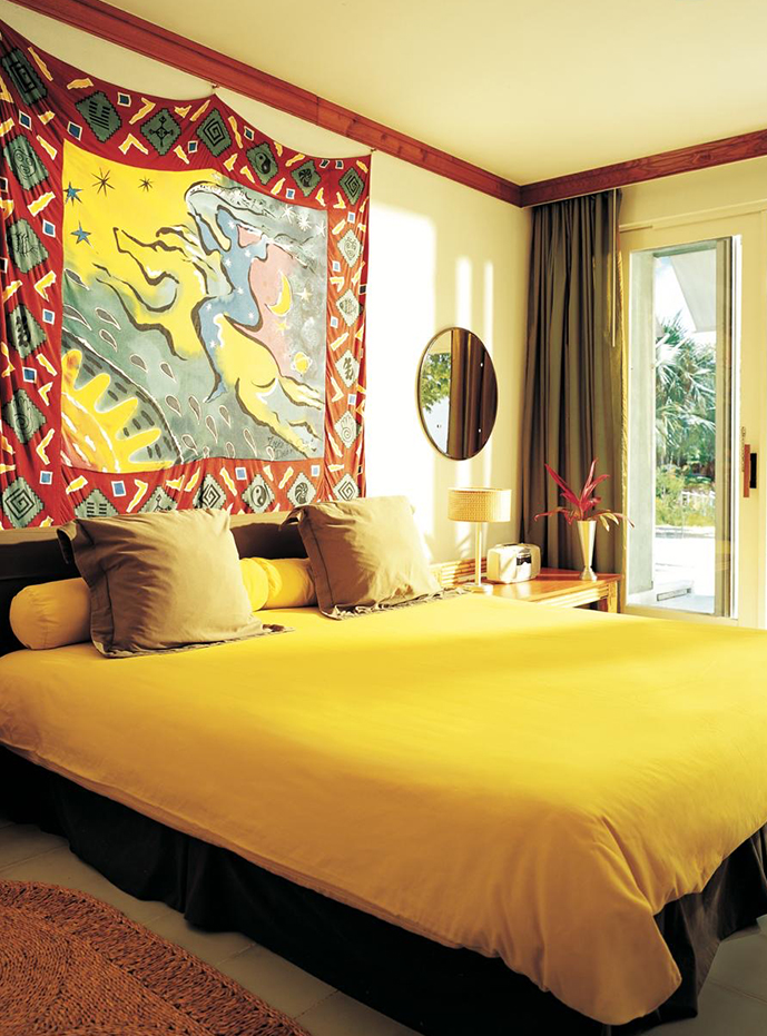 a bed with yellow sheets and pillows