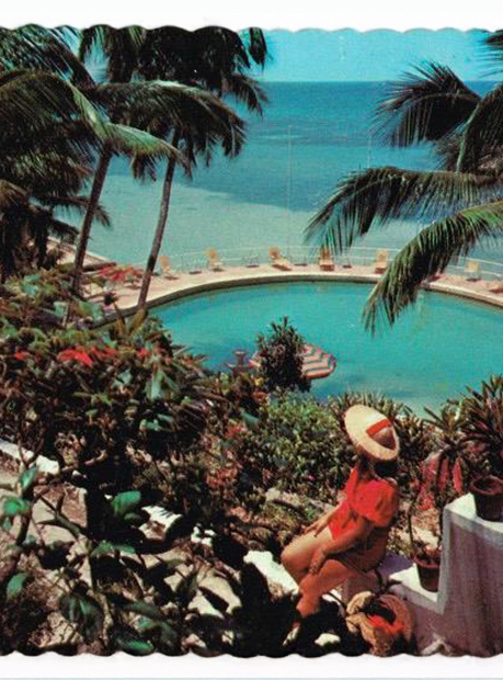 a woman sitting on a ledge overlooking a pool