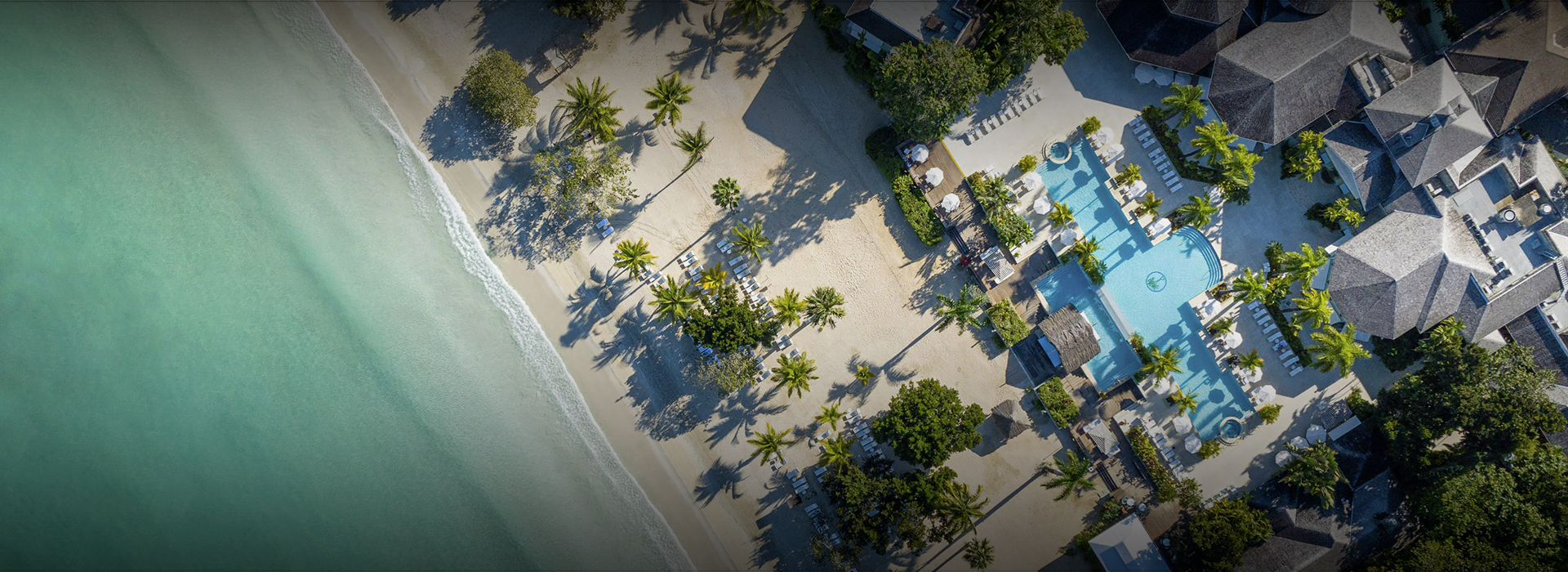 an aerial view of a beach with palm trees and a swimming pool