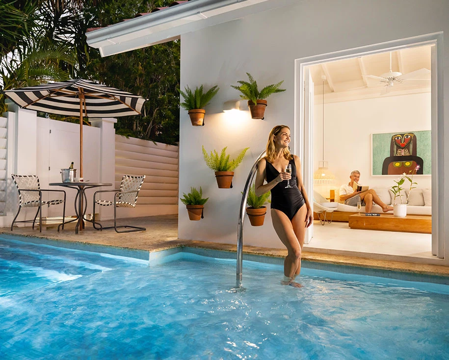 a woman in a swimsuit holding a drink in a pool