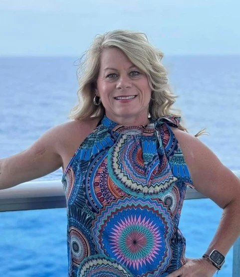 a woman standing on a railing with a body of water behind her