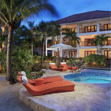 a pool with lounge chairs and palm trees in front of a building
