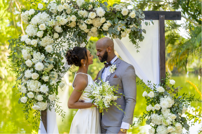 a man and woman in wedding attire under a floral arch