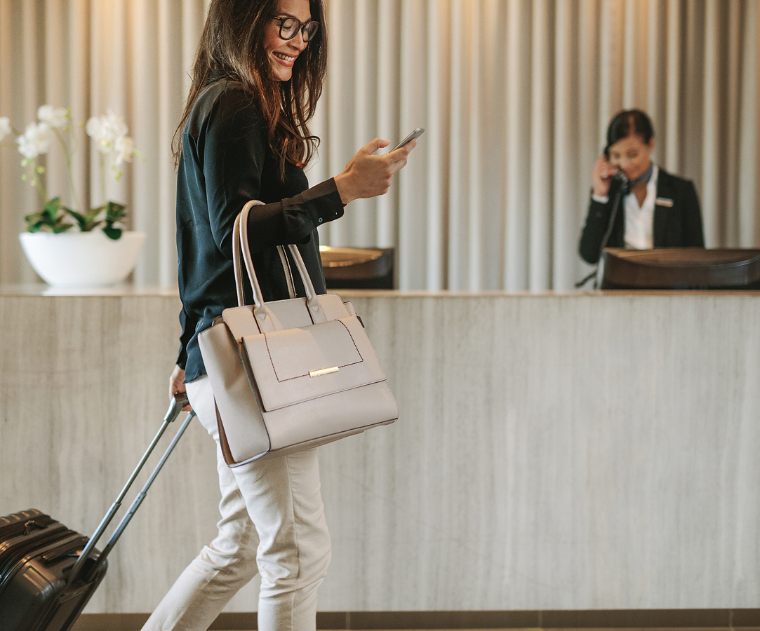 a woman walking with a luggage and a phone