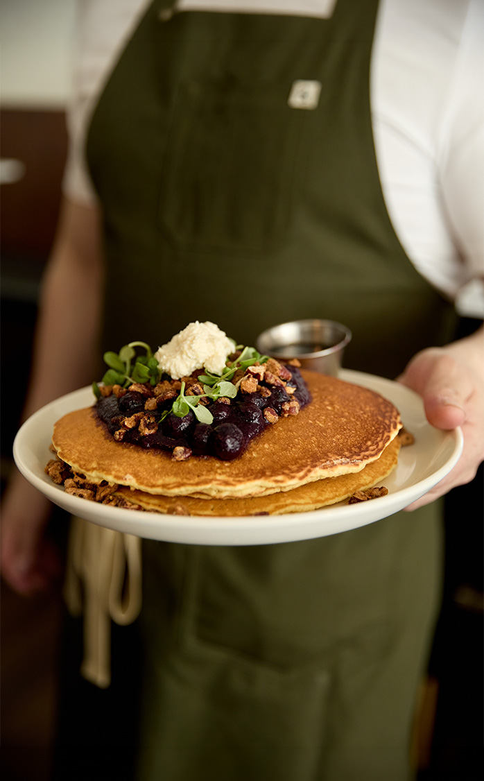 a person holding a plate of pancakes