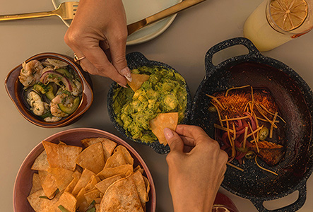a person holding a chip in a bowl of food