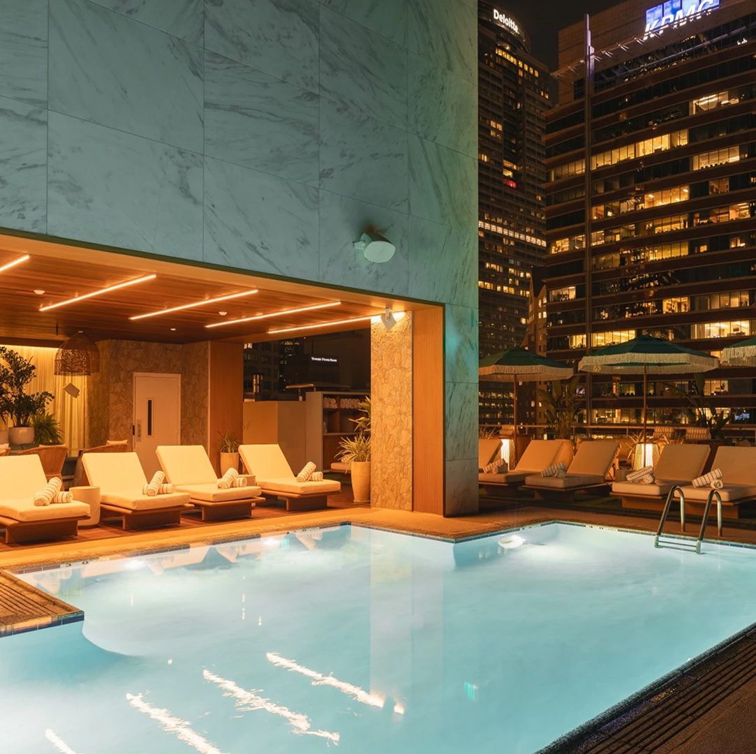 a pool with lounge chairs and umbrellas in front of a building expanded