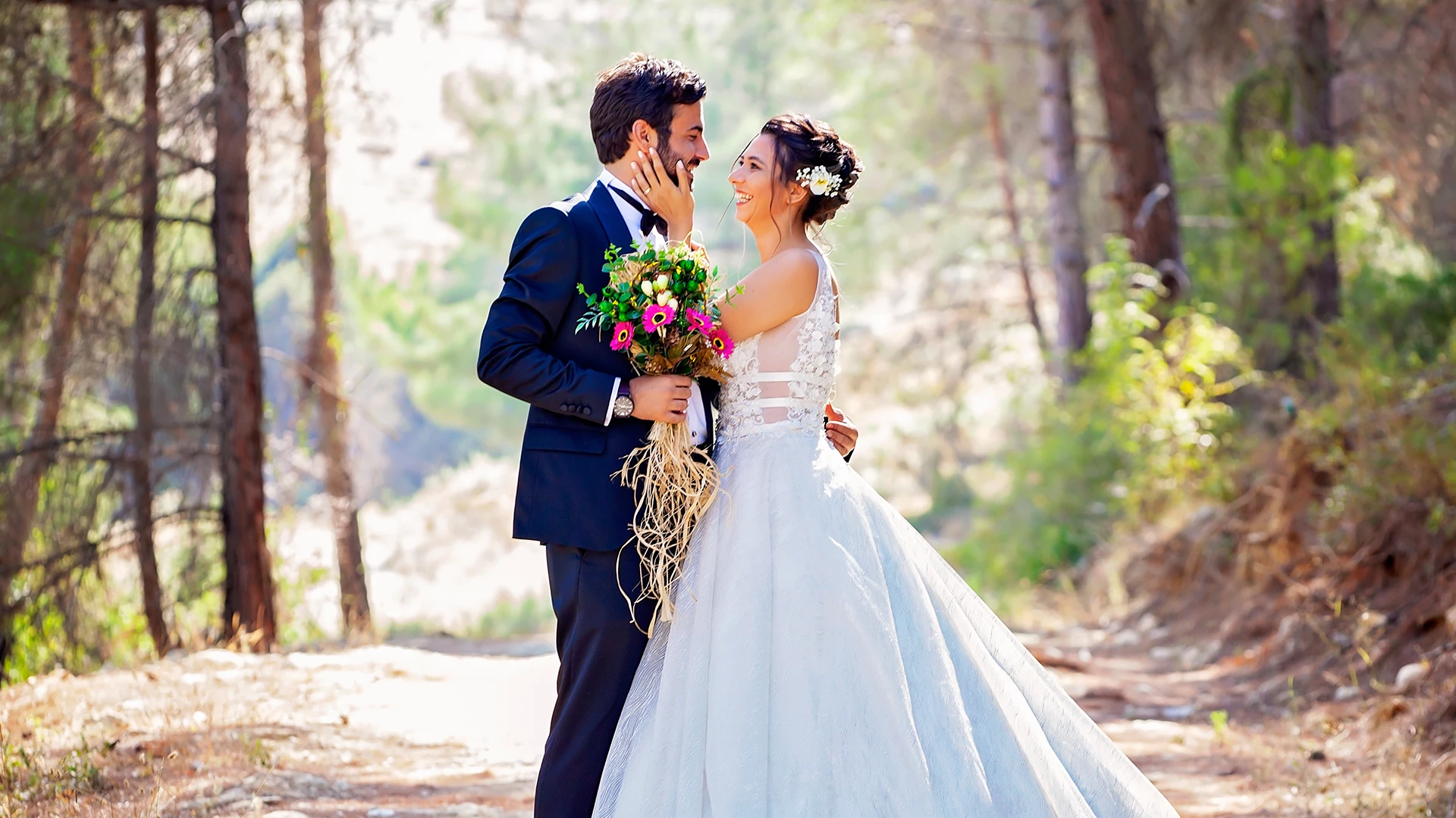 a man and woman in wedding attire in the woods on a trail