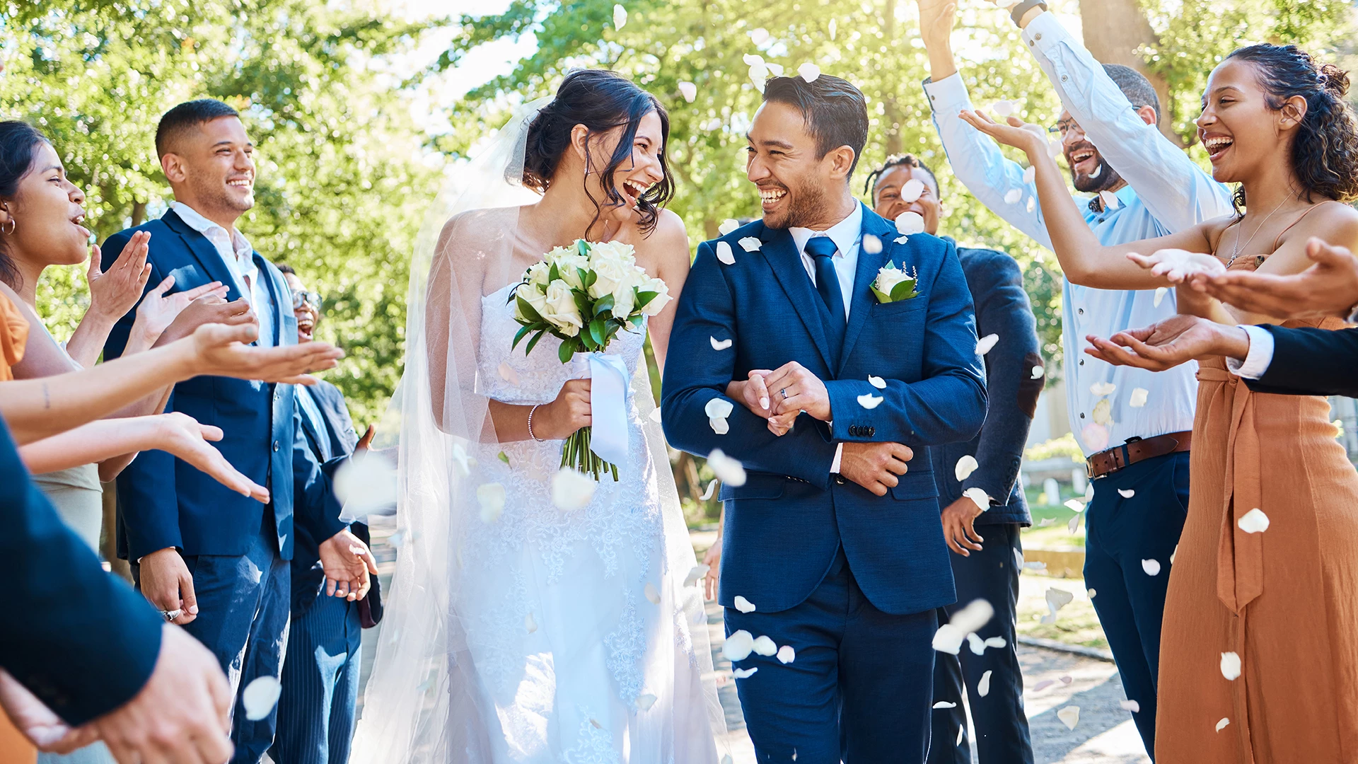 a man and woman walking down the aisle with white petals falling down