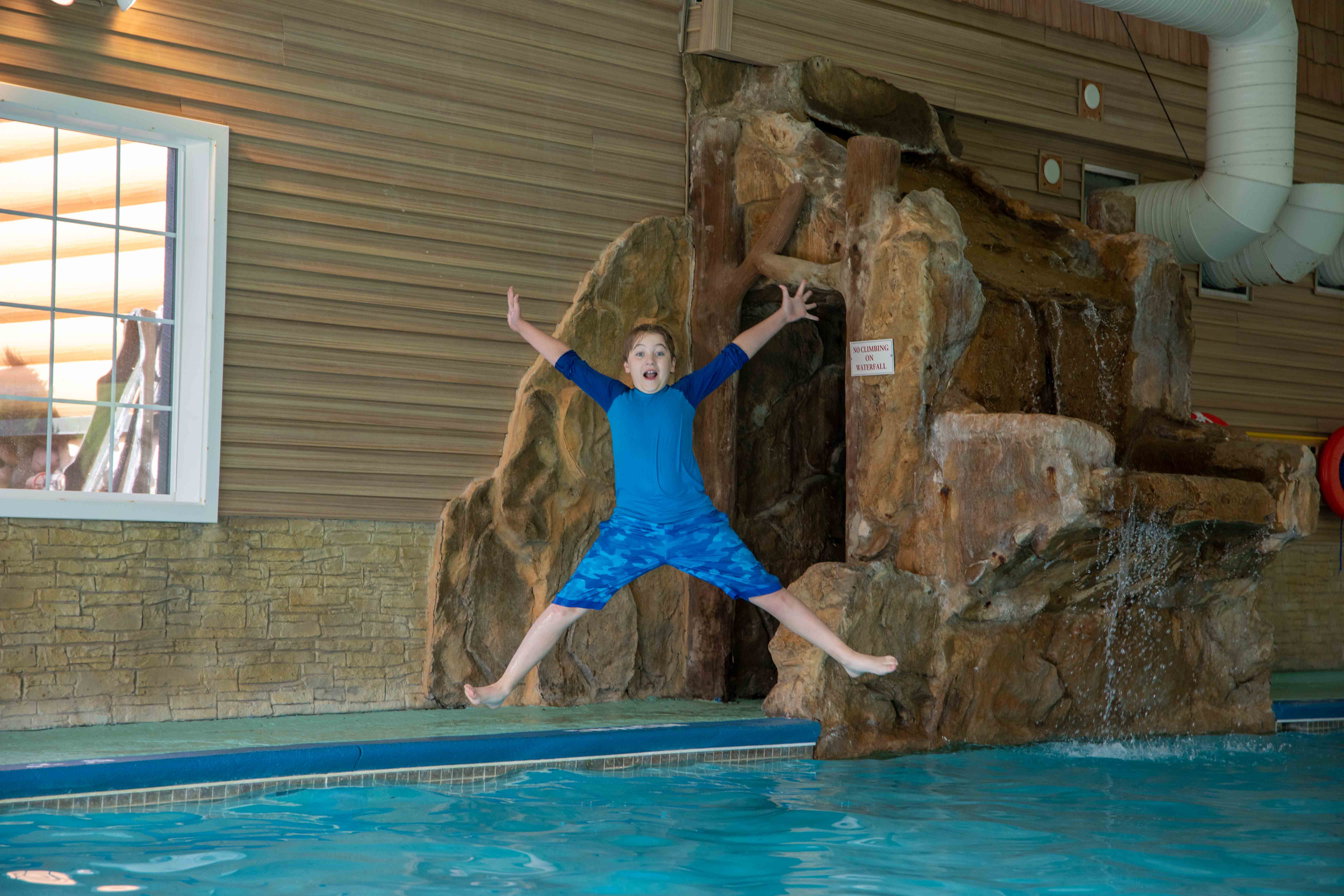 a boy jumping in a pool