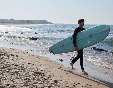 a man carrying a surfboard on a beach