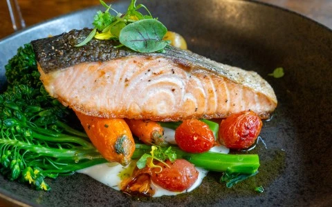 a plate of food with vegetables and a piece of fish