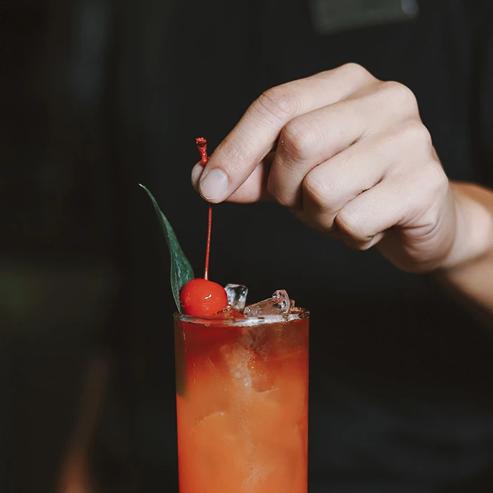 a person holding a string to a glass of liquid