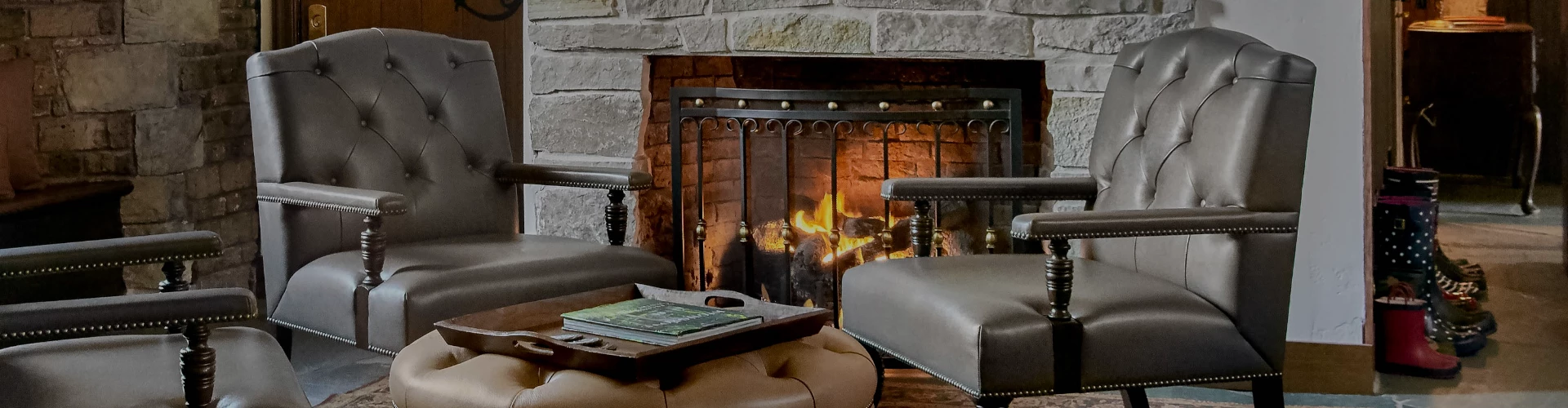 a fireplace with a stone wall and chairs