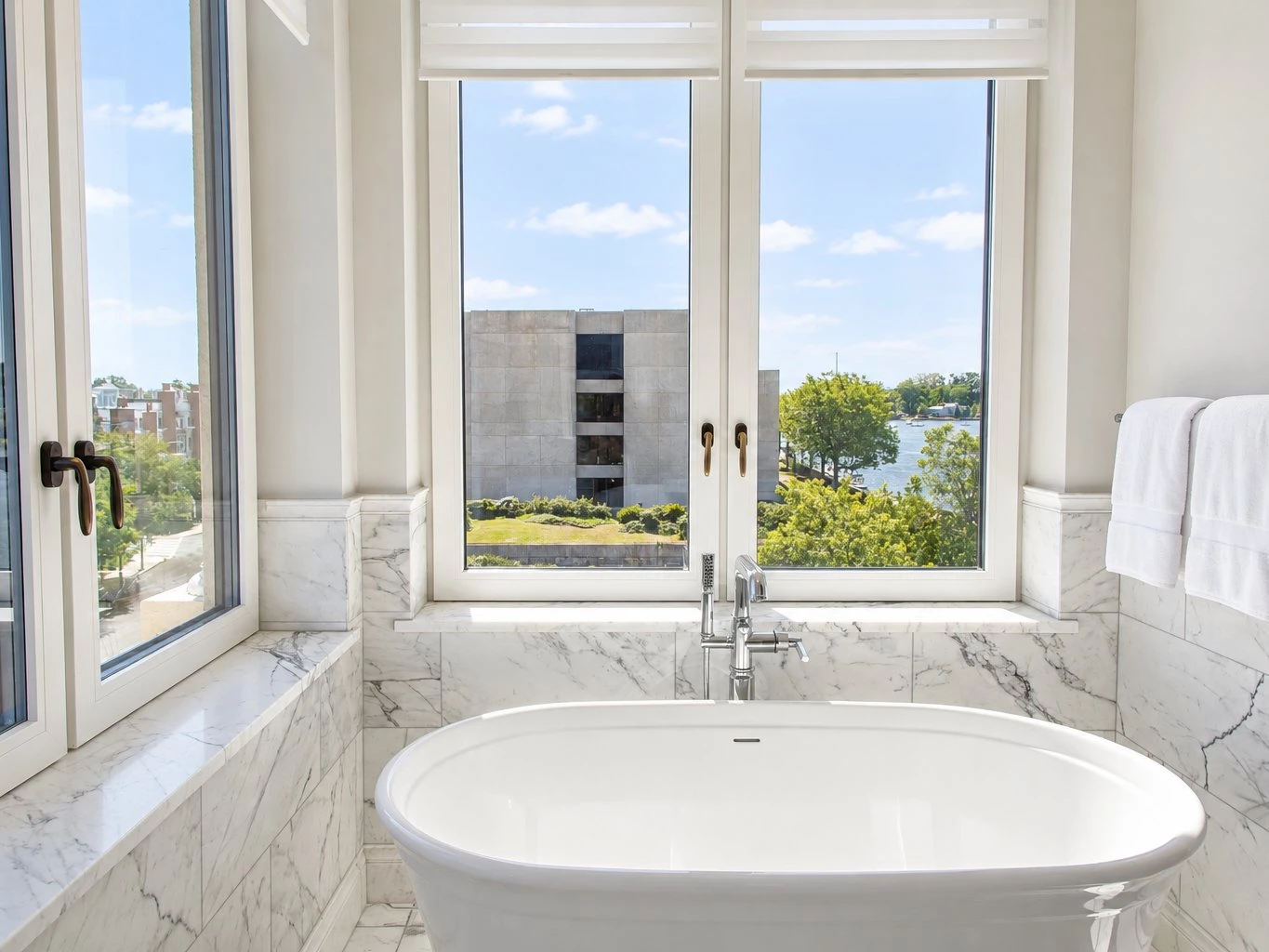 A white soaking tub in front of a large window with a view