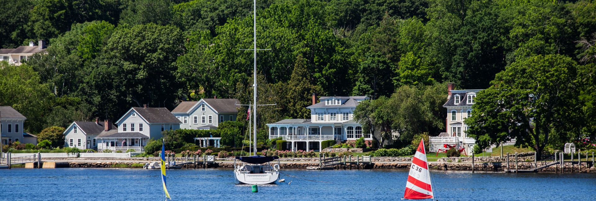 a sailboat in the water with houses in the background