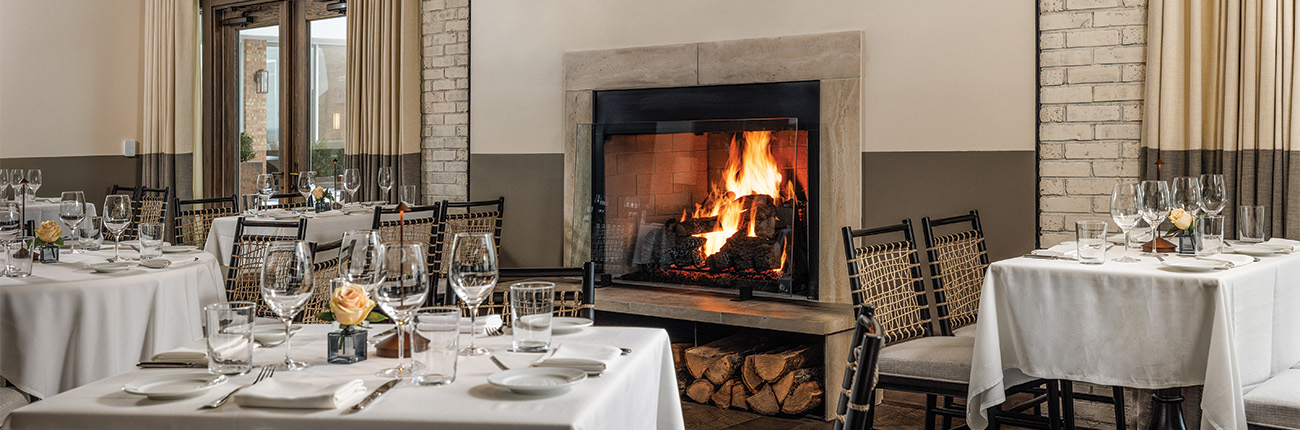 a table set for dinner with a fireplace and glasses on it