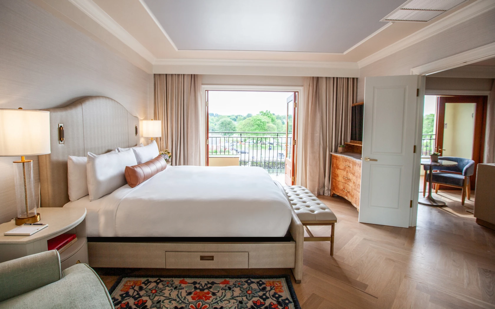 A hotel room with a large bed, balcony, and TV