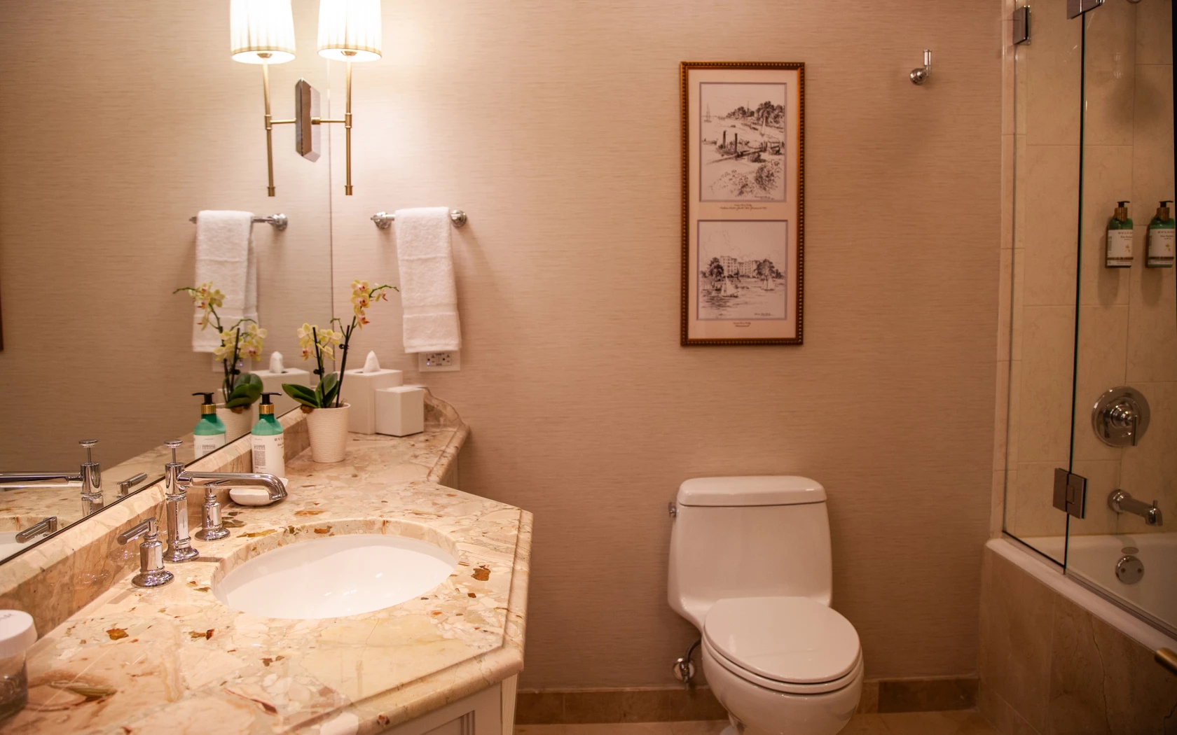 A clean and well-appointed bathroom with a marble countertop, double sink, and tiled shower