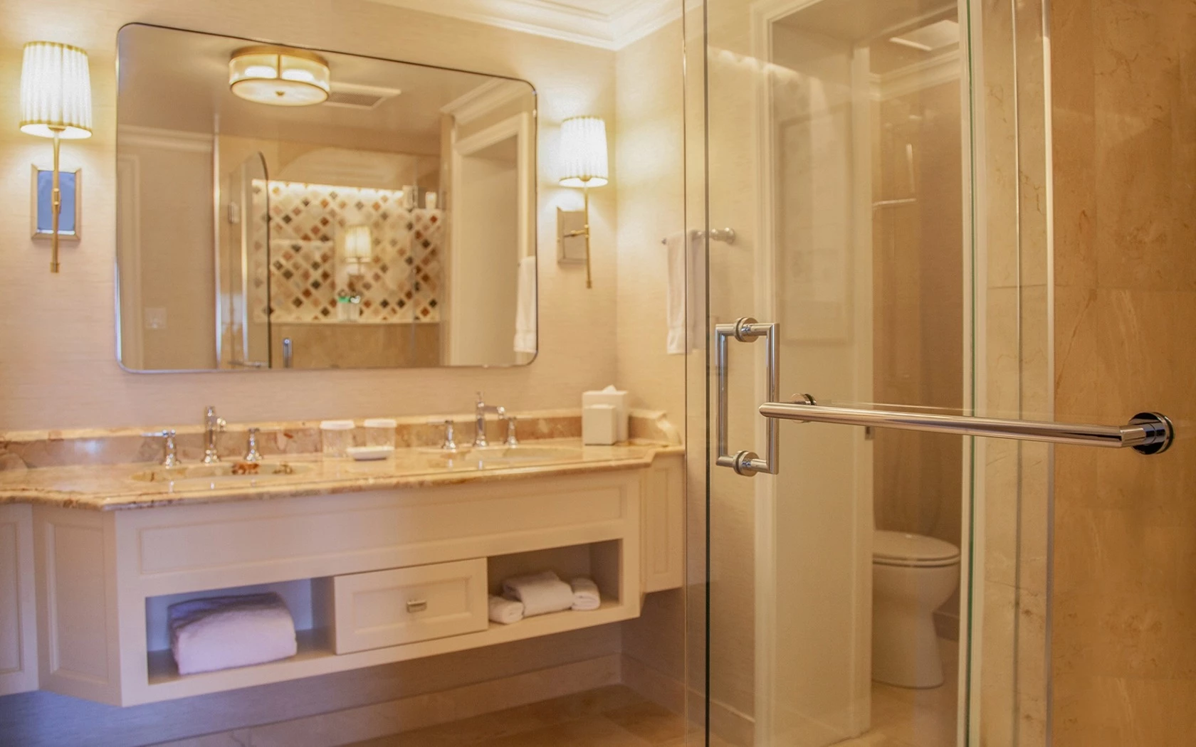 A clean and luxurious bathroom with a double vanity, glass-enclosed shower, and marble countertop.