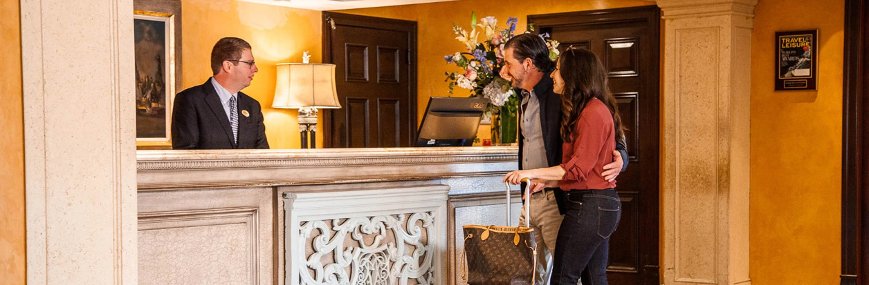 a man and woman standing next to a counter checking into hotel