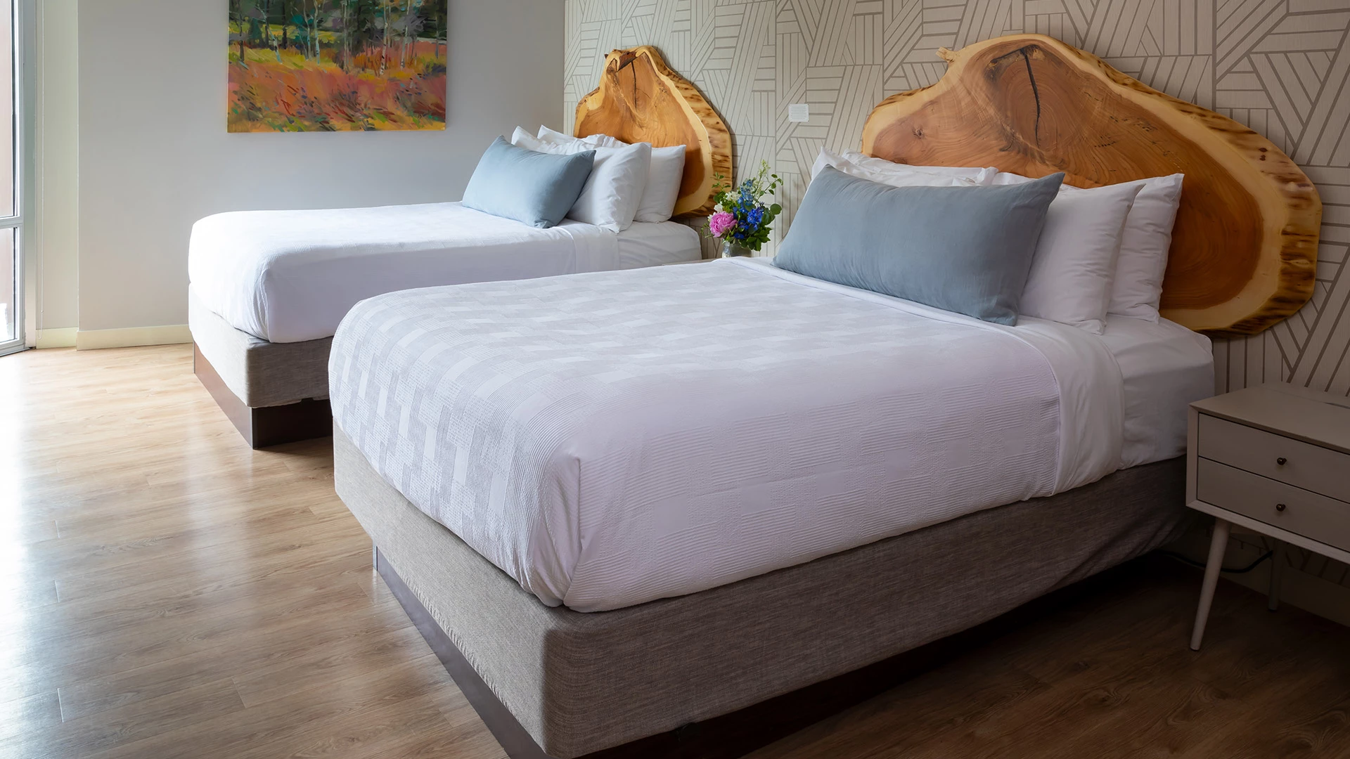 A hotel room with two beds, wooden headboards, and white bedding.