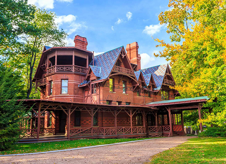a large brick house with a porch and trees with Mark Twain House in the background