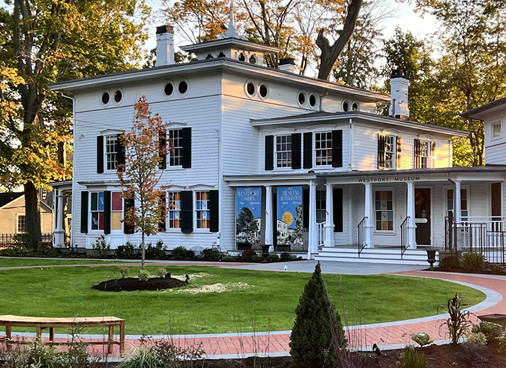 a white building with a lawn and trees