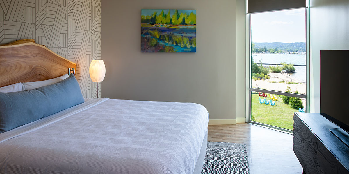 a bed with a lamp and a painting on the wall