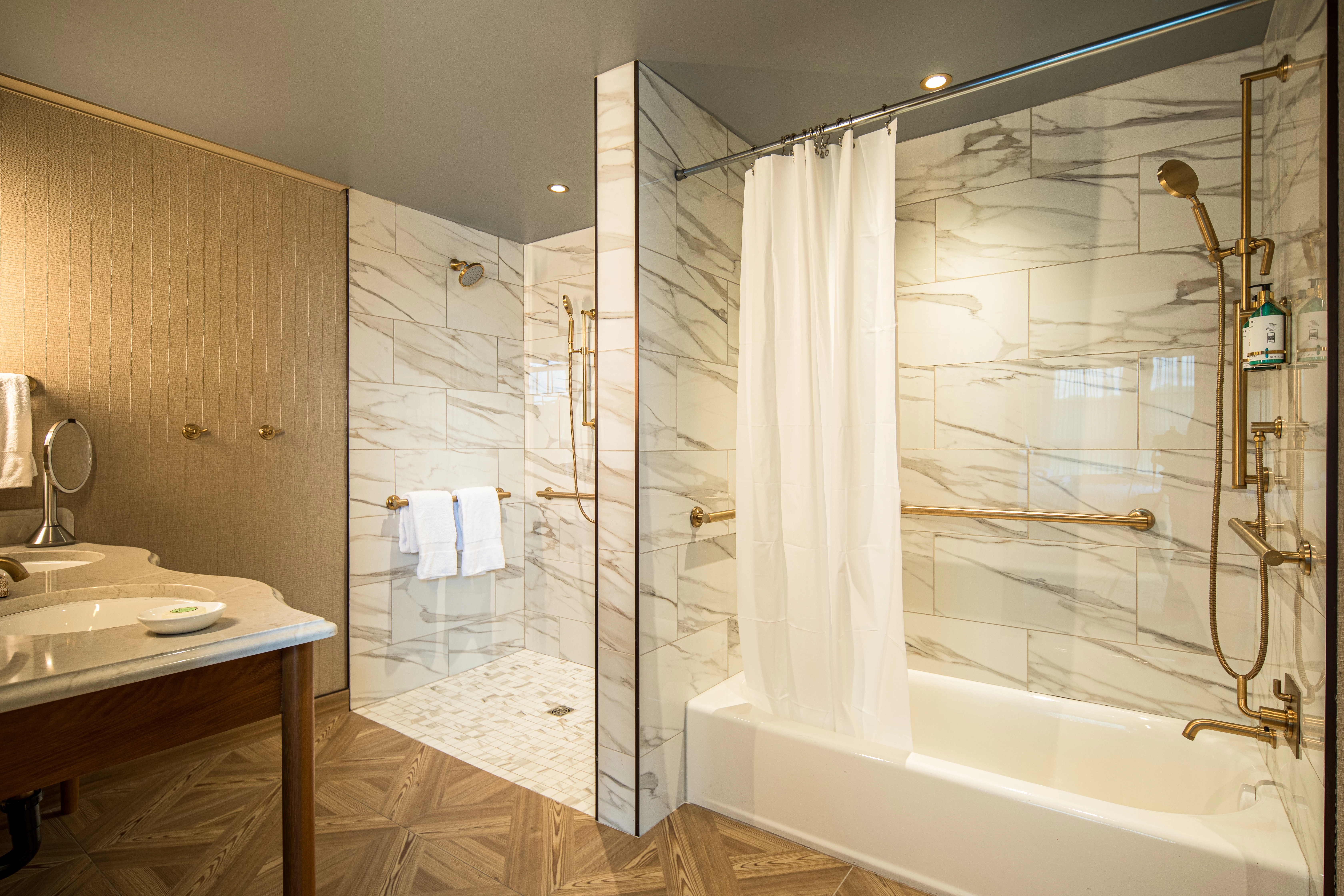 A bathroom with a marble shower, bathtub, and gold fixtures.