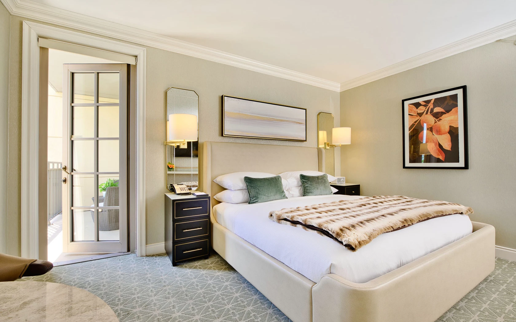 A hotel room with a large bed, nightstand, and balcony door