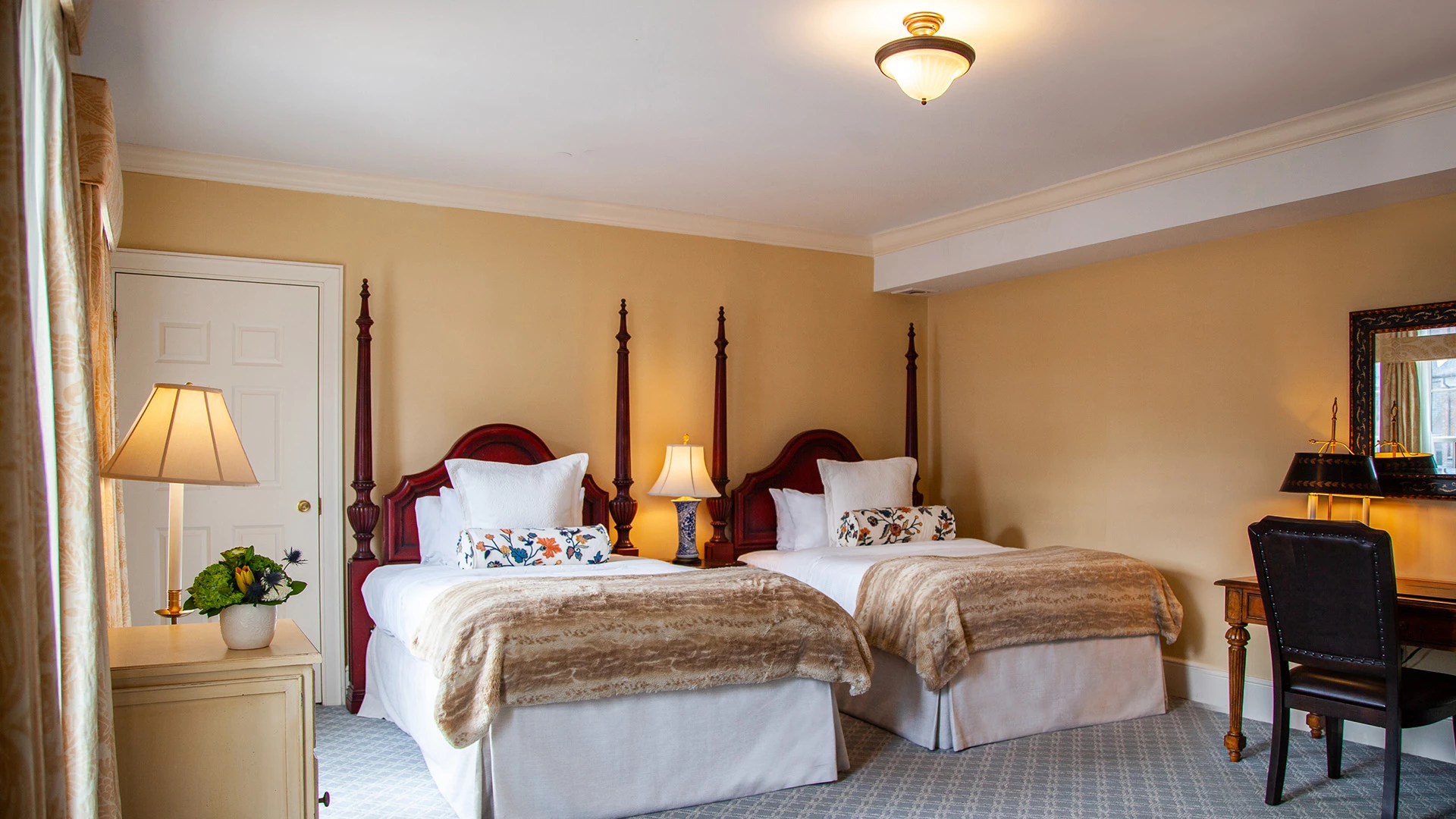 A hotel room with two twin beds, a desk, and a mirror.