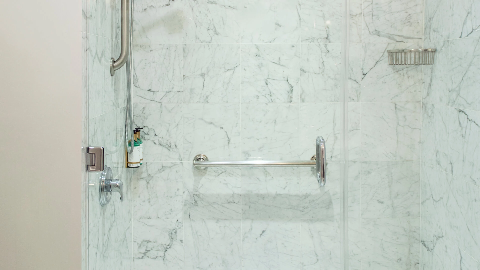 A shower with marble tiles and a grab bar