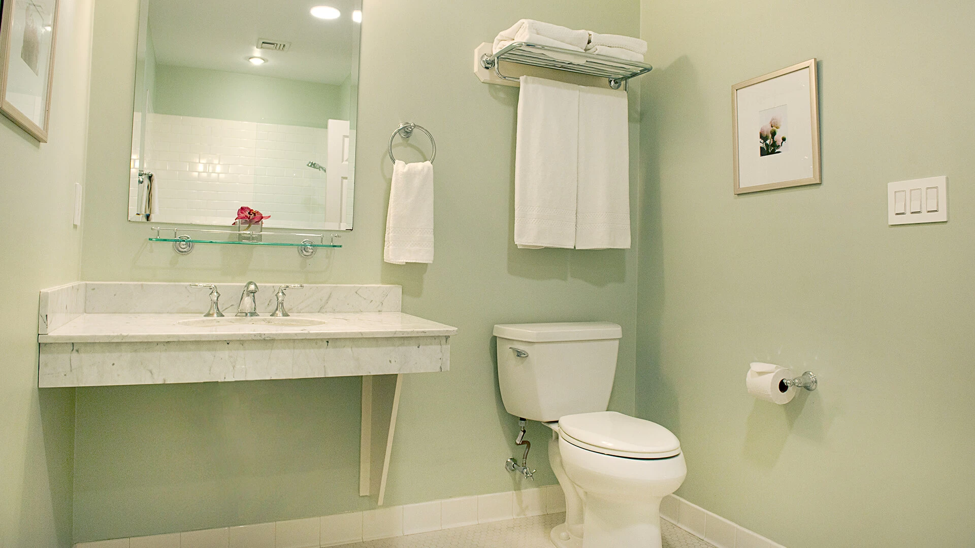 A clean and well-appointed bathroom with a marble sink, toilet, and mirror.