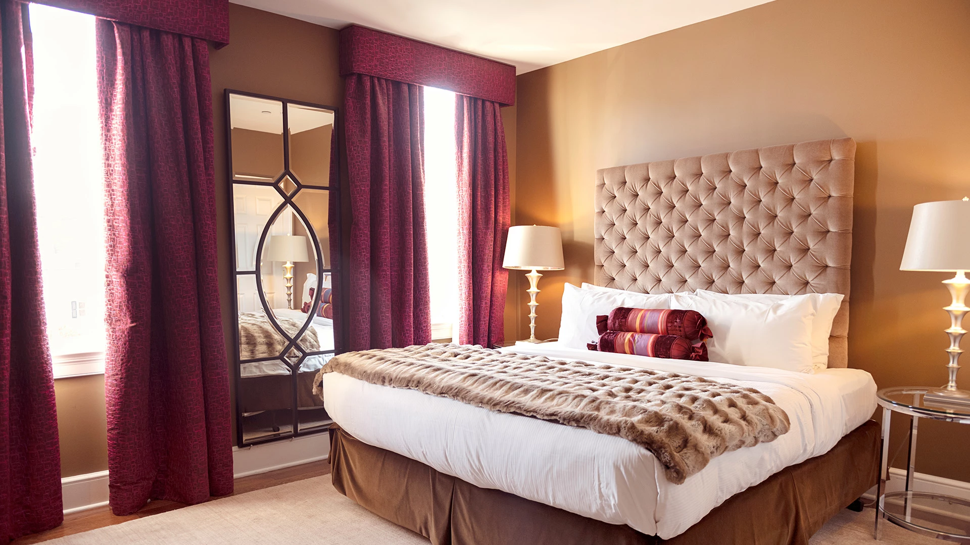 A hotel room with a large bed, mirror, and window