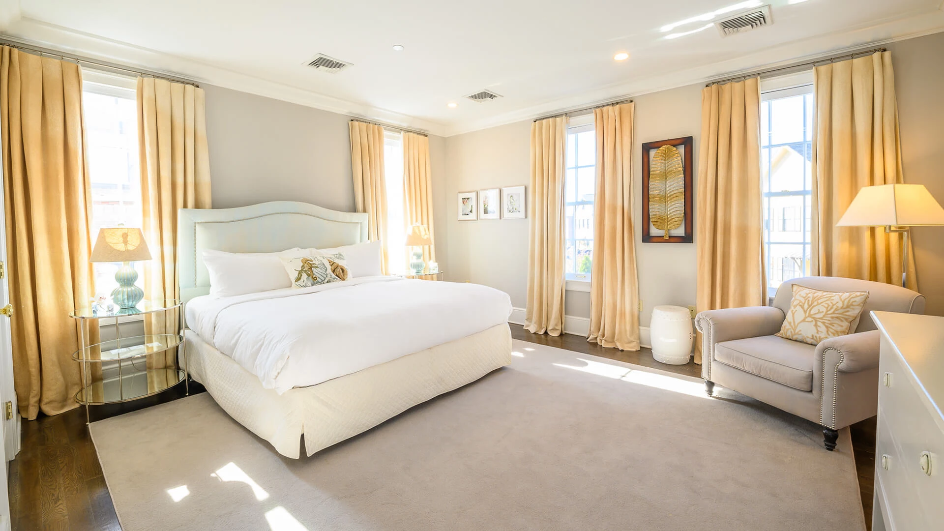 A large hotel room with a bed, chair, and window.