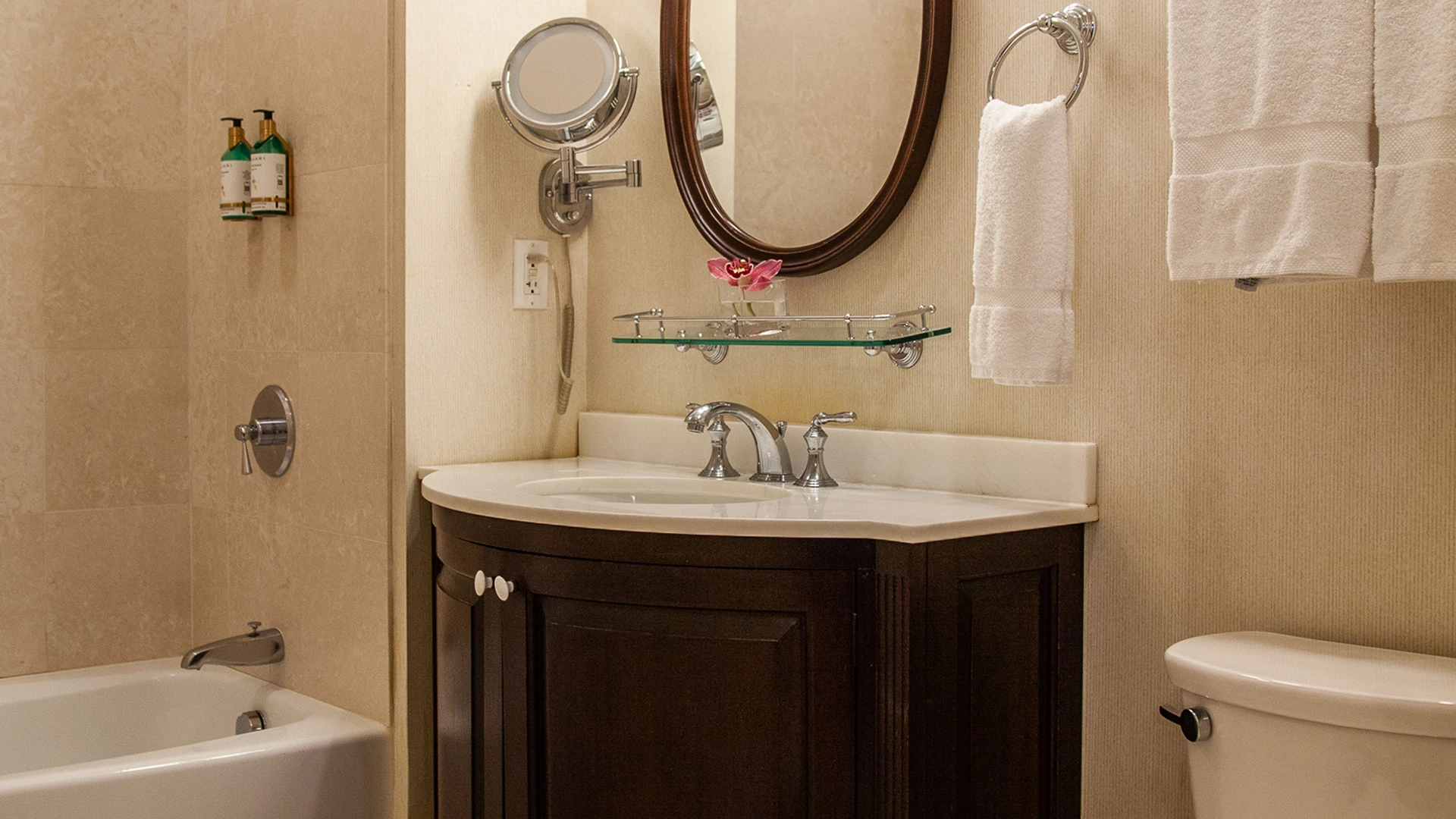 A clean bathroom with a sink, toilet, shower, and towels.