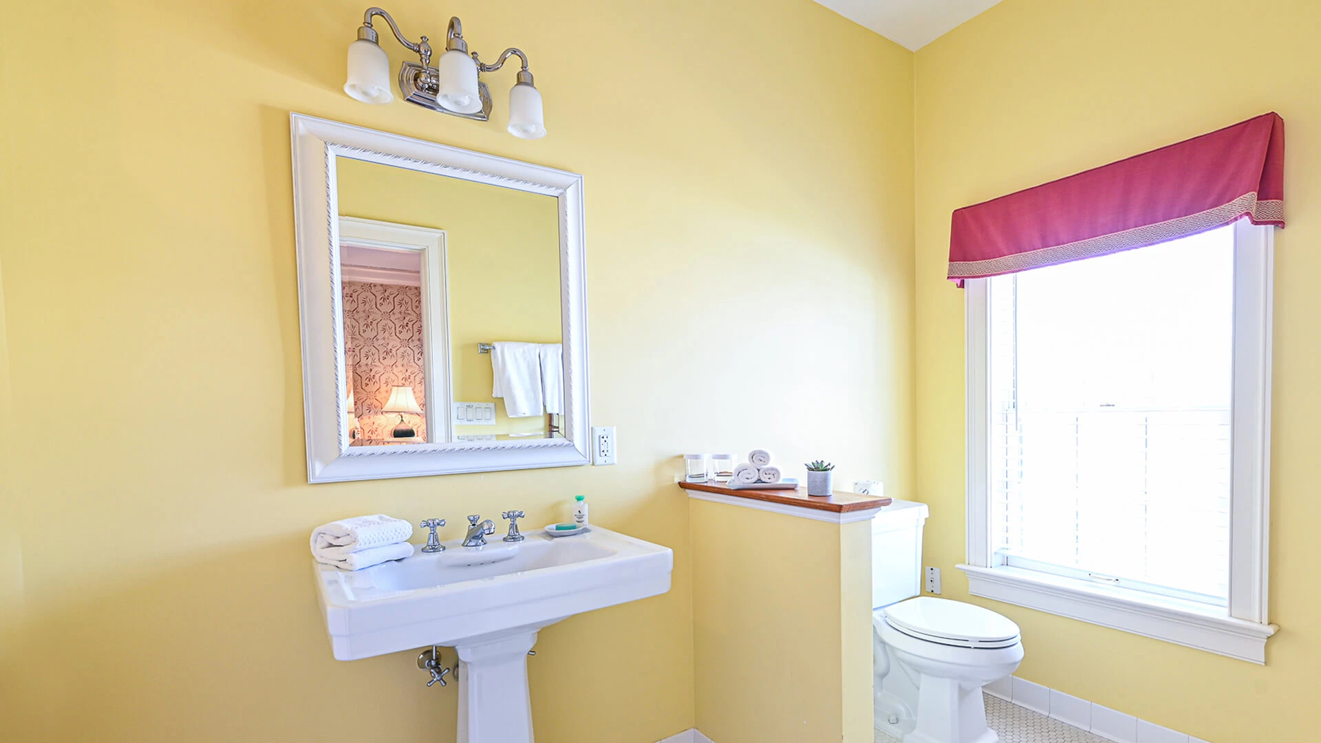 A clean bathroom with a white sink, toilet, and mirror