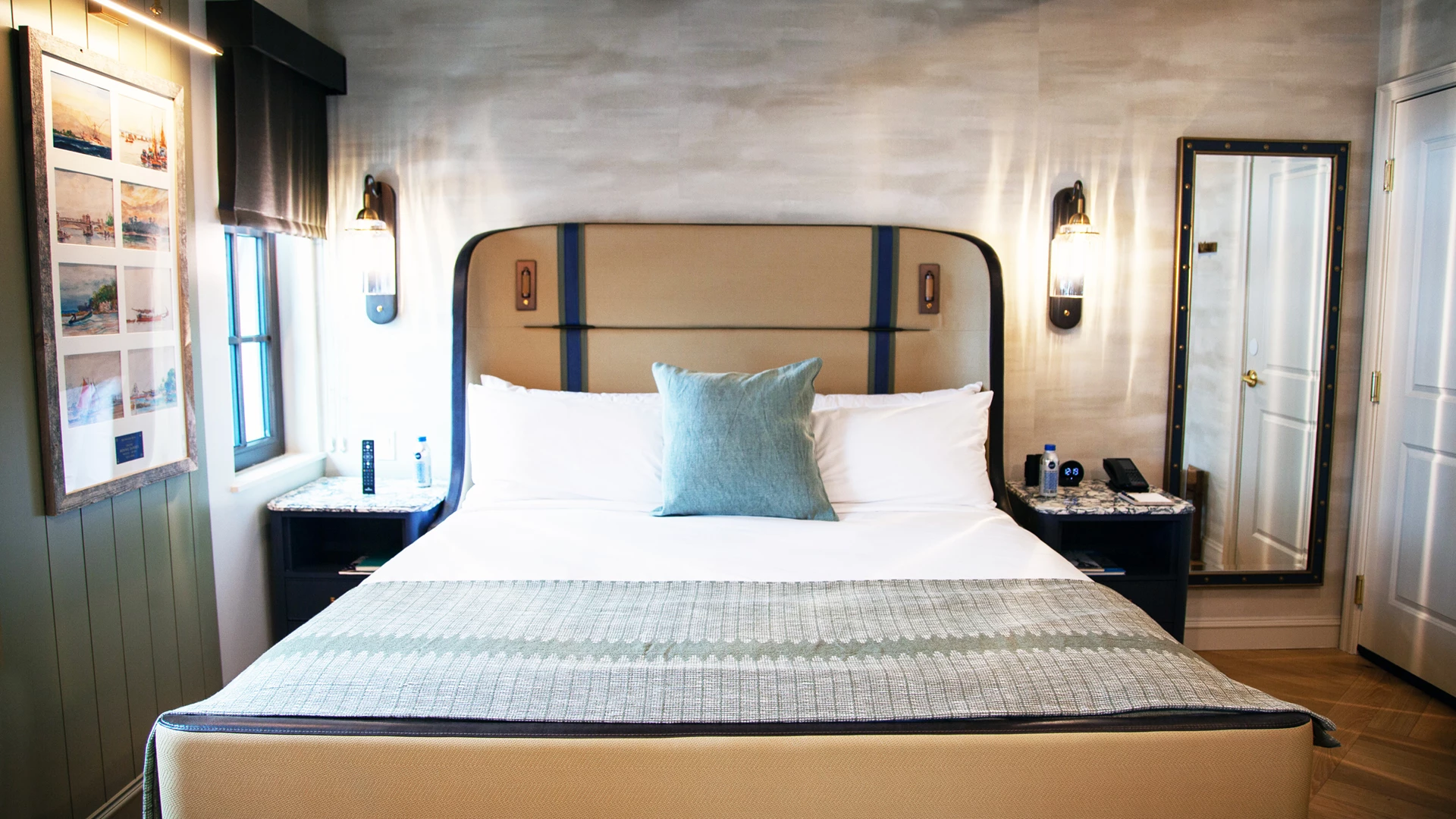 A hotel room with a large bed, nightstands, a mirror, and a window.