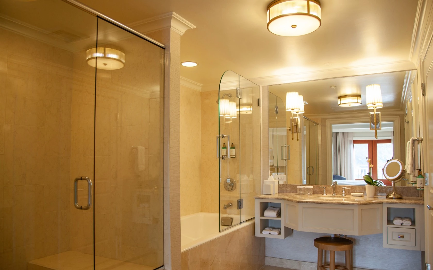 A luxurious bathroom with a glass-enclosed shower, bathtub, and marble countertops.